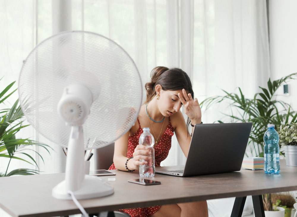 woman hot in house using fan