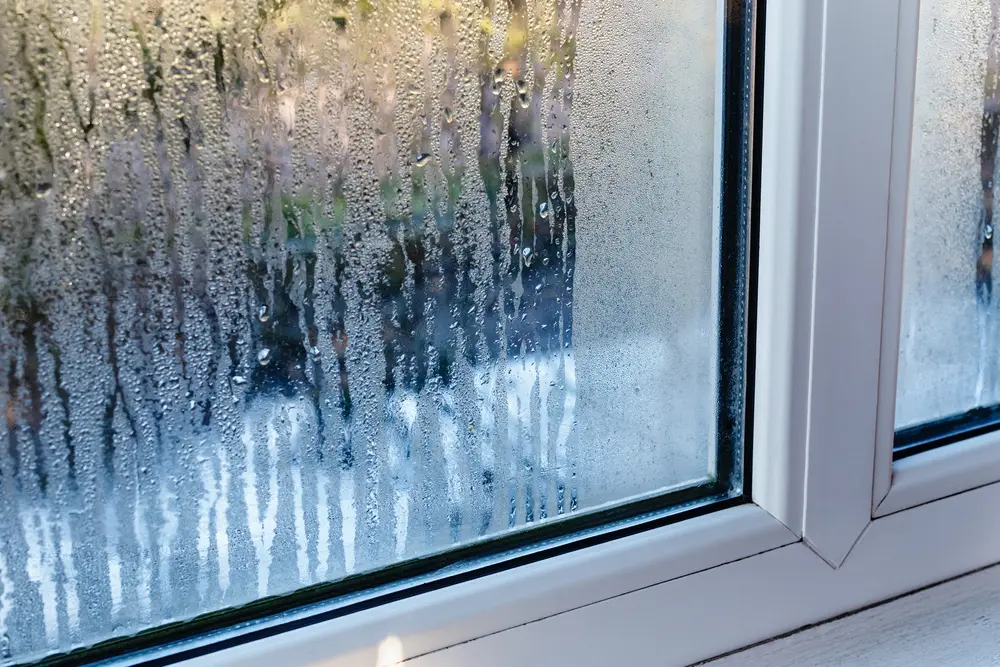 How to Control Humidity in Your Home - Charles Stone – Heating and Cooling Drops of condensation on the metal-plastic window. Fragment of a plastic window with water condensation on the glass, temperature difference, cooling, humidity in the room.