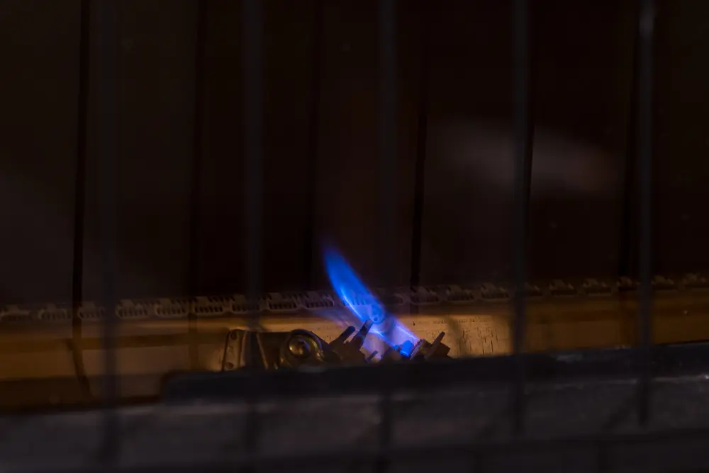 Furnace Not Turning On? Here's Why - Charles Stone – Heating and Cooling Small pilot flame for gas furnace heater. Constant blue flame for igniting main burners, behind safety grill.