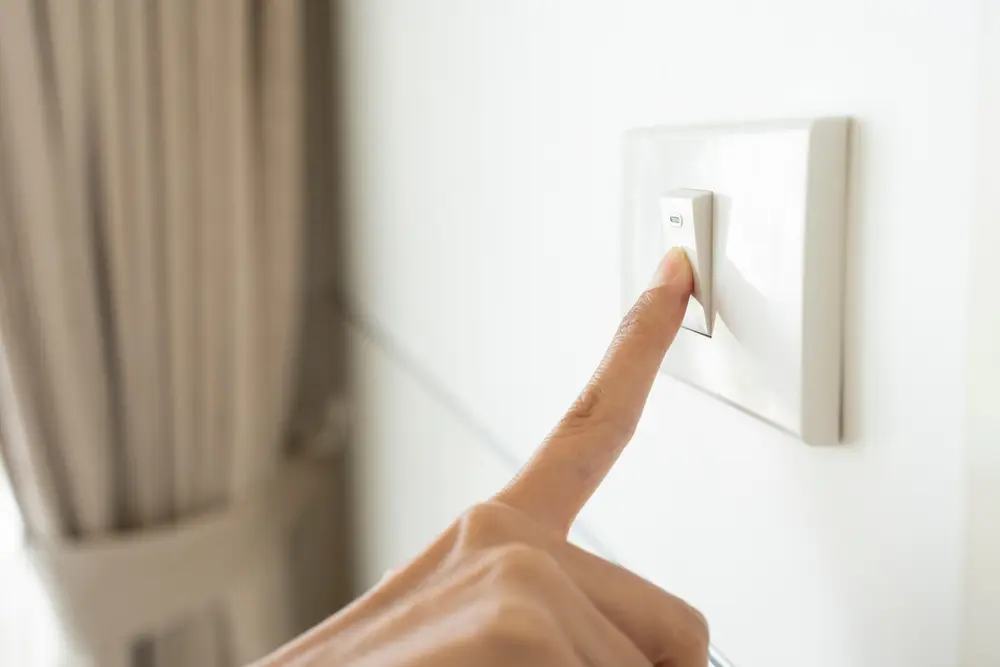 Furnace Not Turning On? Here's Why - Charles Stone – Heating and Cooling close up hand of woman turning on or off light switch in a home.